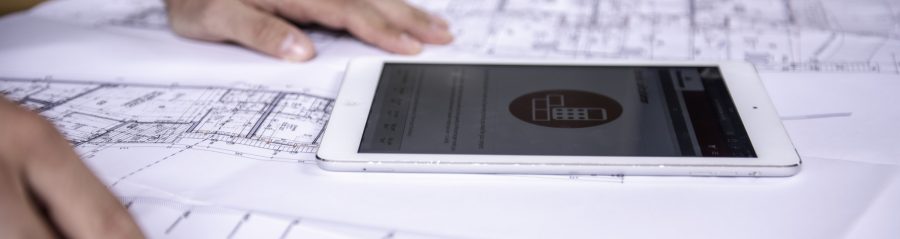 Tablet computer and hands at blueprint