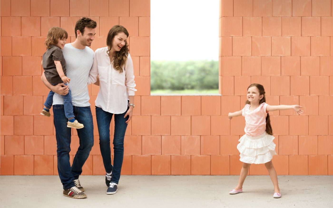 Parents watching girl in joy over her future room in building shell