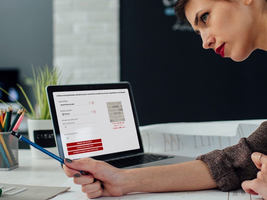 Female architect working in her new modern office. Standing and examining blueprints for her new project. There are on the desk in front of her laptop, architectural model on new business building and color swatch.